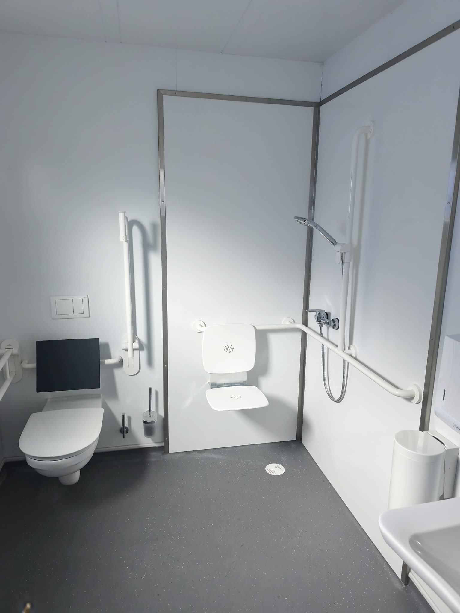 Exemple de salle d’eau avec barres d’appui et siège de douche